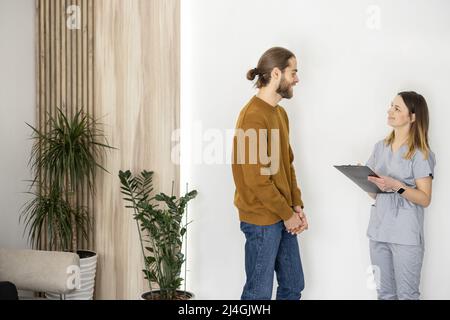 Der Arzt kommuniziert mit dem männlichen Patienten an der Rezeption der Klinik Stockfoto