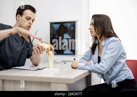 Junge Frau in Absprache mit einem Physiotherapeuten in der Arztpraxis Stockfoto