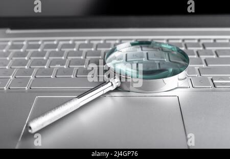 Lupe auf der Laptop-Tastatur. Informationssuche über Internet-Konzept. Online-Schulungen. Expertise in elektronischen Projekten, Finanzdaten. Hochwertige Fotos Stockfoto