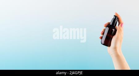 Ein Modell eines braunen Dispensers mit einem Naturkosmetikprodukt in der Hand einer Frau auf blauem Hintergrund. Null West. Stockfoto