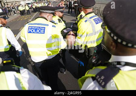 Eine Frau wird von der Polizei fortgetragen, nachdem sie an einem Extinction Rebellion Protest auf der Westminster Bridge in London teilgenommen hat. Bilddatum: Freitag, 15. April 2022. Stockfoto