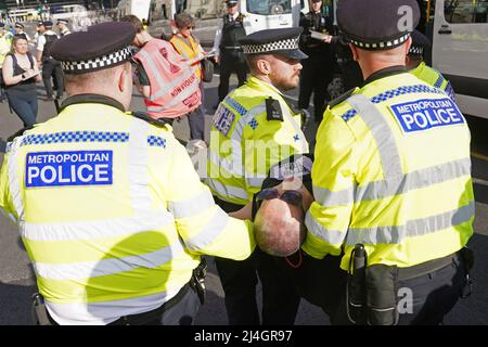 Eine Frau wird von der Polizei fortgetragen, nachdem sie an einem Extinction Rebellion Protest auf der Westminster Bridge in London teilgenommen hat. Bilddatum: Freitag, 15. April 2022. Stockfoto