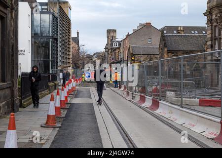 Mann, der während der Bauarbeiten auf Straßenbahnlinien auf einem Elektroroller reitet, Constitution Street, Leith, Edinburgh, Schottland, VEREINIGTES KÖNIGREICH Stockfoto