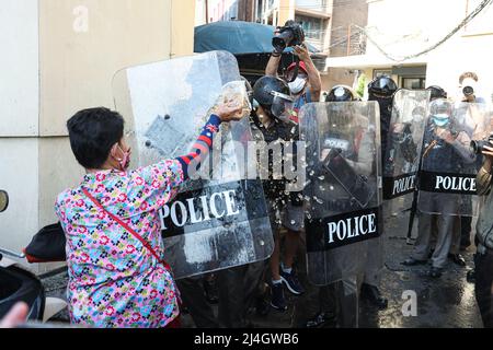 Bangkok, Thailand. 13. April 2022. Einer der Demonstranten warf ein Glas alkoholfreies Getränk auf einen Polizeibeamten, der einen Schild in der Hand hielt. (Foto: Adirach Toumlamoon/Pacific Press/Sipa USA) Quelle: SIPA USA/Alamy Live News Stockfoto