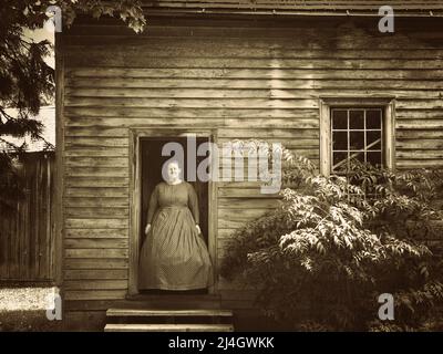 Toronto, Kanada - 08 11 2011: Ein Museumsmitarbeiter in Kleidung aus dem 19.. Jahrhundert vor der Haustür des Mennonite Meeting House, einem denkmalgeschützten Gebäude von 1824 Zoll Stockfoto