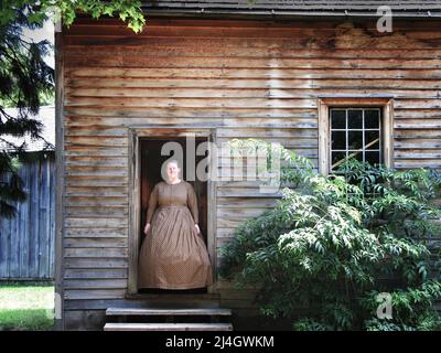 Toronto, Kanada - 08 11 2011: Ein Museumsmitarbeiter in Kleidung aus dem 19.. Jahrhundert vor der Haustür des Mennonite Meeting House, einem denkmalgeschützten Gebäude von 1824 Zoll Stockfoto