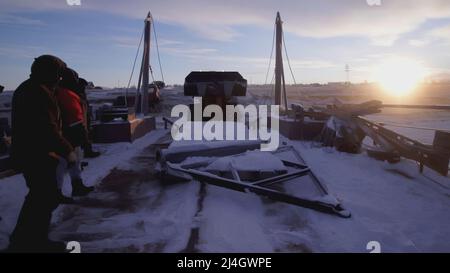 MOSKAU, RUSSLAND - 25. FEBRUAR 2022 : Männer beobachten, wie ein Bulldozer eine schwere Sache wegnimmt. CLIP. Im Norden tragen schwere Geräte Gewichte. Blauer Himmel Stockfoto
