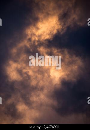 Aufziehende Sturmwolken werden in einem goldenen Ton von der untergehenden Sonne beleuchtet. Stockfoto