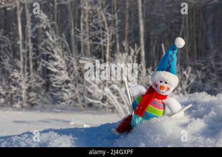 Ein lächelnder, glücklicher Schneemann auf Skiern, umgeben von einer Winterlandschaft Stockfoto