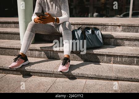 Fit Frau in Sportkleidung mit Smartphone, Ruhe im Freien nach dem Training im Fitnessstudio Stockfoto