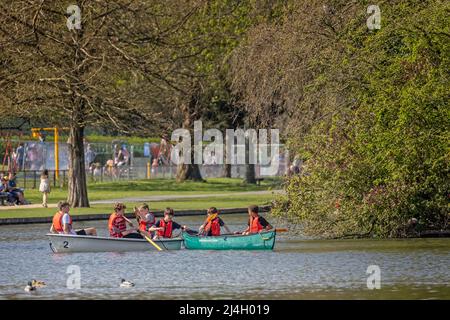 Eine Gruppe junger, multirassischer Jungen, die sich am 15. April 2022 in einem Kanu und einem Ruderboot auf dem Warminster Lake in Warminster, Wiltshire, Großbritannien, Vergnügen Stockfoto