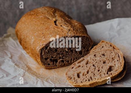 Brot, traditionelles Sauerteigbrot in Scheiben geschnitten auf einem rustikalen Holzhintergrund. Konzept der traditionellen Backmethoden für gesäuertes Brot. Gesunde Ernährung Stockfoto