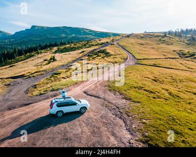 Luftaufnahme der Frau auf dem Dach des suv-Autos sitzen genießen die Aussicht. Road Trip. Sommerzeit. Dragobrat karpaten in der Ukraine Stockfoto