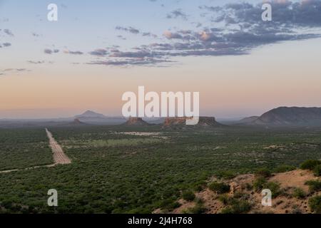 Namibia, Landschaft im Damaraland, mit großen Felsen und einer unbefestigten Straße bei Sonnenuntergang Stockfoto