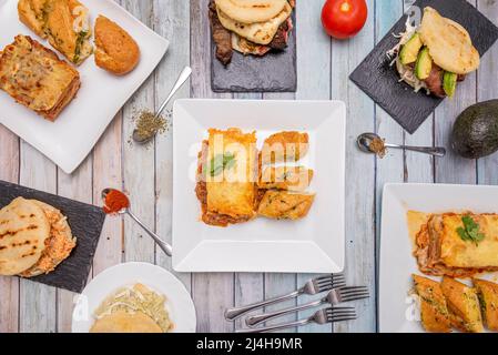 Venezolanische und italienische Fast-Food-Gerichte und Vorspeisen, verschiedene Arapas mit Huhn, Fleisch und Avocado, Fleisch- und Gemüselasagne Stockfoto