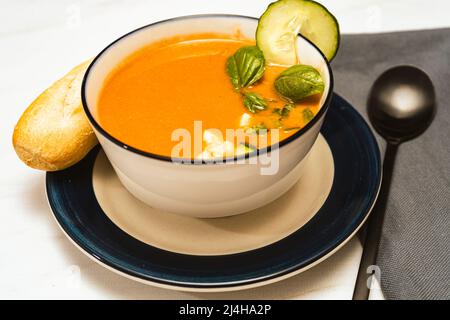 Moderne weiße Schale mit andalusischem Gazpacho. Gemüse- und Bio-Suppe oder kaltes Getränk, das im Sommer getrunken wird. Stockfoto