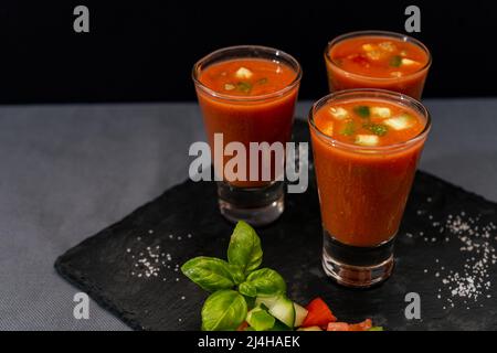 Kleine Gläser Schuss oder Likör mit andalusischem Gazpacho. Eine kalte Gemüse- und Bio-Suppe oder ein Getränk, das im Sommer oder an heißen Tagen getrunken wird. Stockfoto