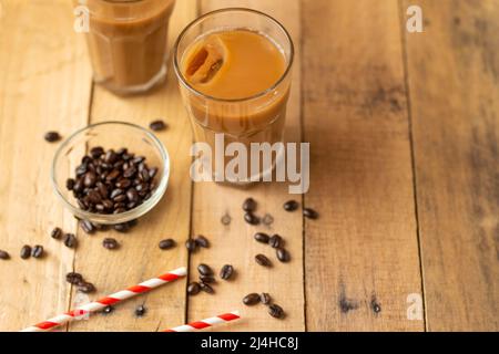 Flach liegend. Kalter Kaffee in transparenten Gläsern mit Eis und Trinkhalmen, auf Holzboden, kühlendes Getränk, erfrischende Sommerstimmung, mit Kopierplatz Stockfoto