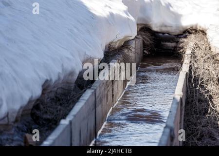 Betonwasserentwässerung während des Frühjahrshochwassers in Vororten Stockfoto