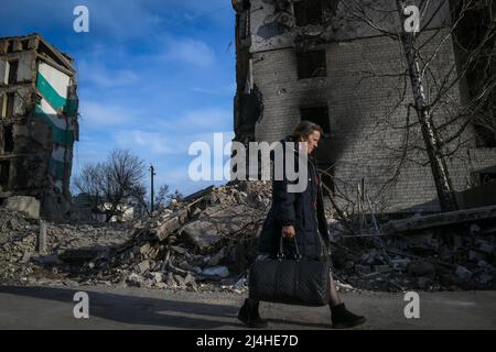 Borodyanka, in der Nähe von Kiew, Ukraine - 15. April 2022: Eine Frau geht vor Gebäude, die während der russischen Besatzung durch Schüsse im Zentrum von Borodyanka beschädigt wurden.Quelle: Piero Cruciatti/Alamy Live News Stockfoto