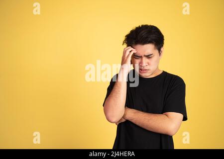 Unsicher, asiatischer junger Mann mit schwarzem Hemd Stockfoto