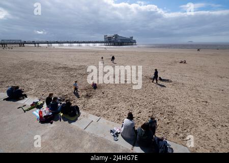 Urlauber genießen den Strand am Weston Super Mare mit dem Grand Pier im Bristol Chanel, Somerset. Stockfoto