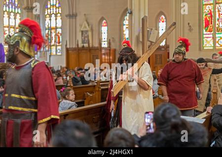 Detroit, Michigan, USA. 15. April 2022. Jesus trägt ein Kreuz und trägt eine Dornenkrone während der Lebendigen Stationen des Kreuzes in der Basilika Ste. Anne de Detroit. Ste. Anne wurde 1701 von französischen Siedlern gegründet. Der Karfreitagsdienst wurde in spanischer Sprache gehalten, was die derzeitige Mitgliedschaft in der Pfarrei widerspiegelt. Kredit: Jim West/Alamy Live Nachrichten Stockfoto