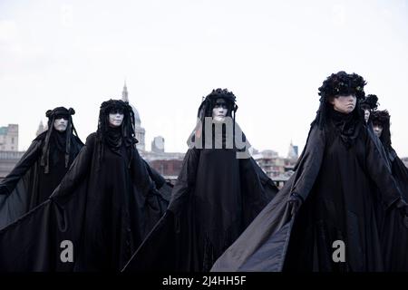 London, Großbritannien. 15. April 2022. Aktivisten werden auf der Bankside auftreten sehen. Aktivisten der Klima-Protestgruppe Extinction Rebellion, die als schwarze Brigaden gekleidet ist, führen in der Öffentlichkeit Pantomimen, Slow-Motion-Bewegungen und Tableaus vor, um gegen die Investition fossiler Brennstoffe durch die britische Regierung und die Auswirkungen fossiler Brennstoffe auf die Umwelt zu protestieren. Kredit: SOPA Images Limited/Alamy Live Nachrichten Stockfoto