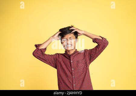 Gestresster junger asiatischer Mann, der den Kopf hält Stockfoto