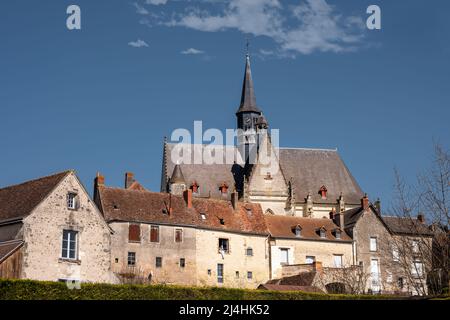 MONTRESOR, FRANKREICH - 24.. MÄRZ 2022: Blick auf die Stiftskirche St. Johannes des Täufers hinter einigen traditionellen Häusern Stockfoto