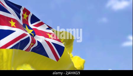 Nahaufnahme der Nationalflagge des Staates Niue, die im Wind winkt. Im Hintergrund ist der Himmel klar. Niue ist ein Inselstaat im Südpazifik Stockfoto