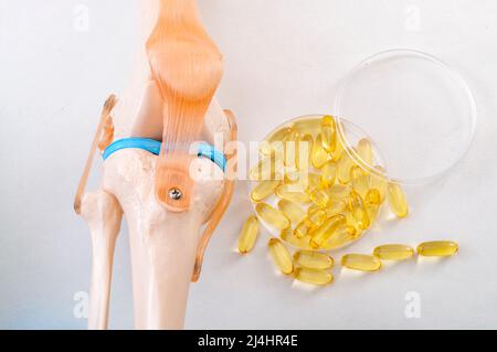 Gelenkgesundheit, gesunde Omega-3-Fettsäuren und reduzieren Arthritis Entzündungskonzept mit plastischem medizinischen Lehrmodell eines menschlichen Knies und Fischöl p Stockfoto