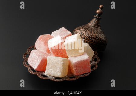Ramadan-Süßigkeiten und süßes Süßes-Konzept aus dem Nahen Osten mit einer Nahaufnahme der türkischen Köstlichkeiten auf einer verzierten Metallplatte isoliert auf schwarzem Hintergrund Stockfoto