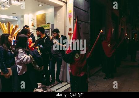 Barcelona, Spanien. 15. April 2022. Während der Karfreitagsprozession zieht ein mit Kapuze behauener Büßer der Bruderschaft "Nuestra Senora de las Angustias" durch Barcelona.Quelle: Matthias Oesterle/Alamy Live News Stockfoto