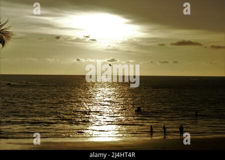 Touristen genießen den Sonnenuntergang am Cenang Strand in Langkawi. Stockfoto