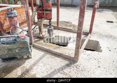 Installation für das Bohren großer Löcher in Betonkonstruktionen, ein Teil der Arbeiten wurde bereits durchgeführt - ein Loch wurde gebohrt, selektiver Fokus Stockfoto