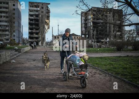 Ukraine. 15. April 2022. Borodyanka, in der Nähe von Kiew, Ukraine - 15. April 2022: Eine Frau geht vor Gebäude, die während der russischen Besatzung durch Schüsse im Zentrum von Borodyanka beschädigt wurden. Russische Streitkräfte betraten das Territorium der Ukraine am 24. Februar 2022. (Foto: Piero Cruciatti/Sipa USA) Quelle: SIPA USA/Alamy Live News Stockfoto