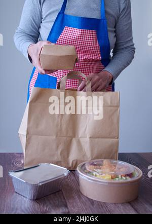 Mittelteil einer Frau, die Essen zum Mitnehmen in einem Papierbeutel zubereitete Stockfoto