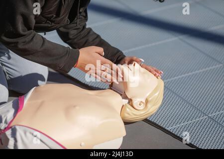 Details mit den Händen einer Studentin, die lernt, wie man eine kardiopulmonale Reanimation (CPR) an einer Schaufensterpuppe zu Bildungszwecken durchführt. Stockfoto