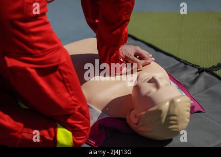 Details mit den Händen eines Notarzthelfers, der die kardiopulmonale Reanimation (CPR) an einer Schaufensterpuppe zu Schulungszwecken durchführt. Stockfoto