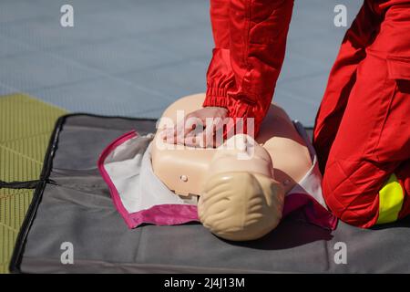 Details mit den Händen eines Notarzthelfers, der die kardiopulmonale Reanimation (CPR) an einer Schaufensterpuppe zu Schulungszwecken durchführt. Stockfoto