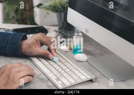 Der Mann, der seine Computertastatur reinigte. Schmutzige, mehr Bakterien auf der Tastatur. Stockfoto