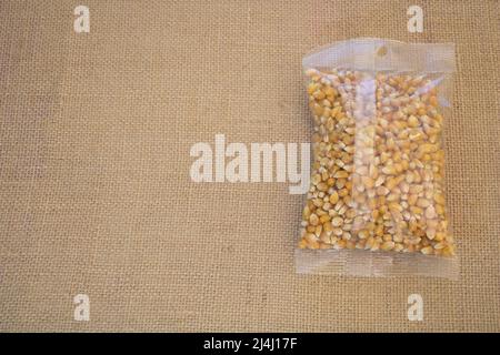 Nahaufnahme des verpackten trockenen Popcorns auf einem Sackleinen-Hintergrund mit Platz für Kopien Stockfoto