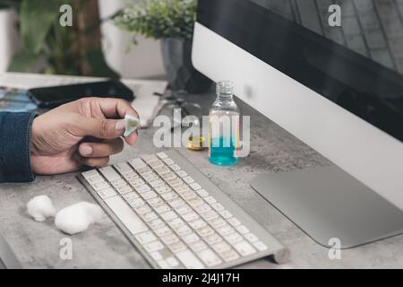 Der Mann, der seine Computertastatur reinigte. Schmutzige, mehr Bakterien auf der Tastatur. Stockfoto