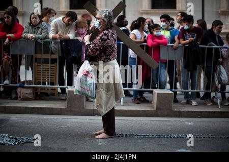 Madrid, Spanien. 15. April 2022. Eine fromme Frau trägt ein Kreuz auf ihrer Schulter und kettet ihre Füße als Buße während der Prozession des Bildes von Jesus von Medinaceli, die durch die Straßen von Madrid ging. Die Prozession von Jesus de Medinaceli durch die Straßen von Madrid ist eine Veranstaltung zur Erinnerung an die Karwoche. Jesus de Medinaceli ist als der Herr von Madrid bekannt und ist das wichtigste Bild der Stadt. (Foto von Luis Soto/SOPA Images/Sipa USA) Quelle: SIPA USA/Alamy Live News Stockfoto