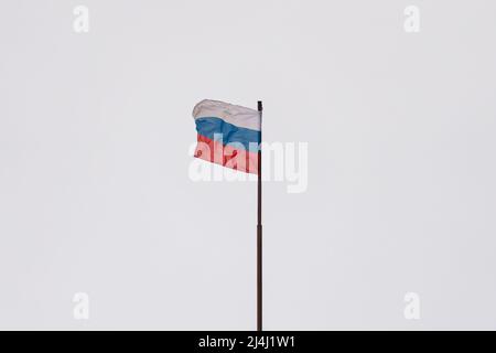 Die Flagge der Russischen Föderation fliegt auf einem Fahnenmast gegen einen grauen Himmel Stockfoto