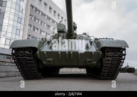 Ein Tank-Symbol auf dem Hintergrund Häuser. Das Konzept der Konfrontation, der Kriegsoperation. Die Offensive der schweren gepanzerten Fahrzeuge auf den Straßen der Stadt Stockfoto