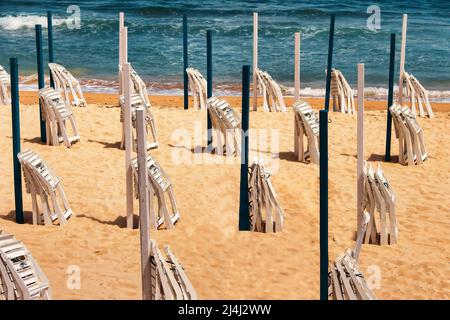 Einsamer Strand mit Klappstühlen und Sonnenschirmen, Konzept der entspannten Freizeit Stockfoto
