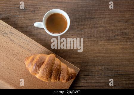 Croissant mit Espresso in weißer Tasse, Draufsicht Stockfoto