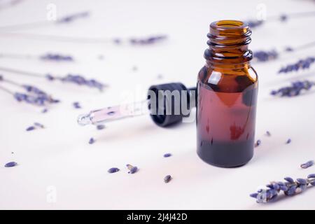 Ätherisches Lavendelöl in einer Glasflasche mit Lavendelblüten im rustikalen Stil, Aromatherapie-Spa-Massagekonzept. Lavendula-Oleum. Stockfoto